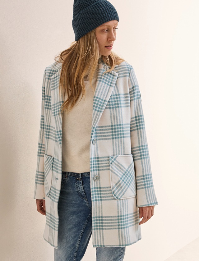 Ein Modell trägt einen blau-weißen karierten Mantel und strahlt Stil und Eleganz aus.