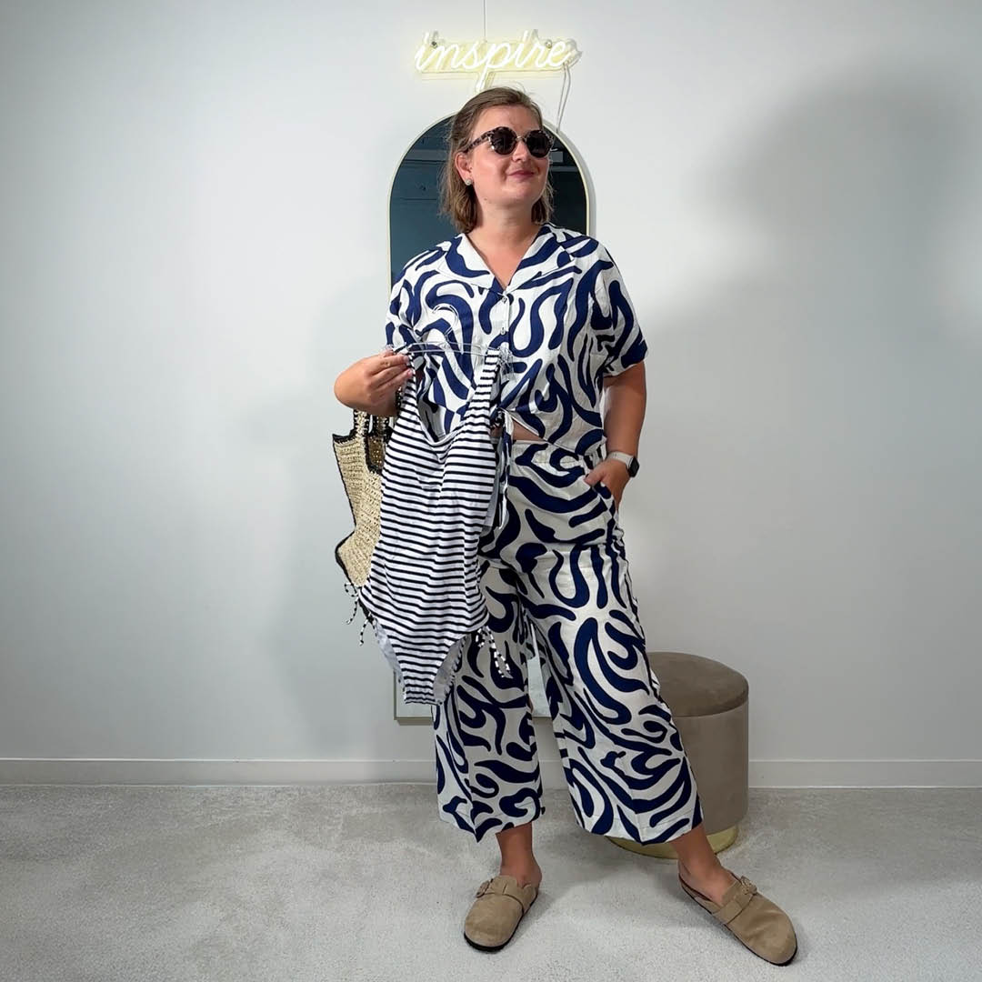 Eine Frau in einem blau-weißen Kleid hält eine Tasche in der Hand. Eine Frau in einem blau-weißen Kleid hält eine Tasche in der Hand.