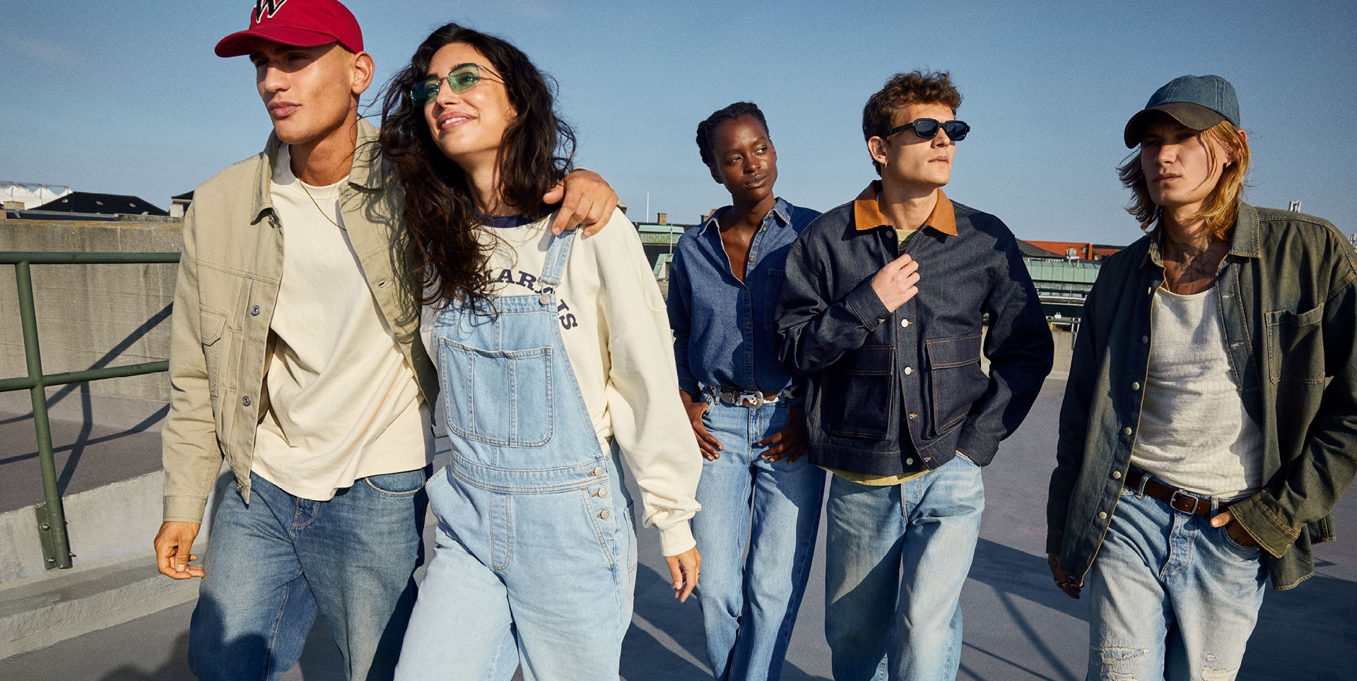 Fröhliche junge Menschen in Denim-Overalls stehen zusammen und genießen den Moment. Fröhliche junge Menschen in Denim-Overalls stehen zusammen und genießen den Moment.