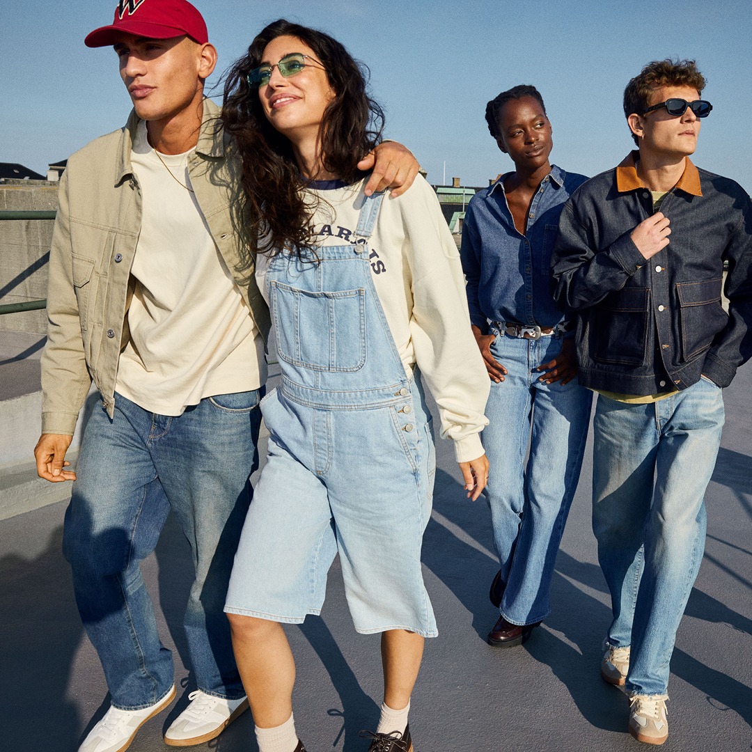 3. Fröhliche junge Menschen in Denim-Overalls stehen zusammen und genießen den Moment.