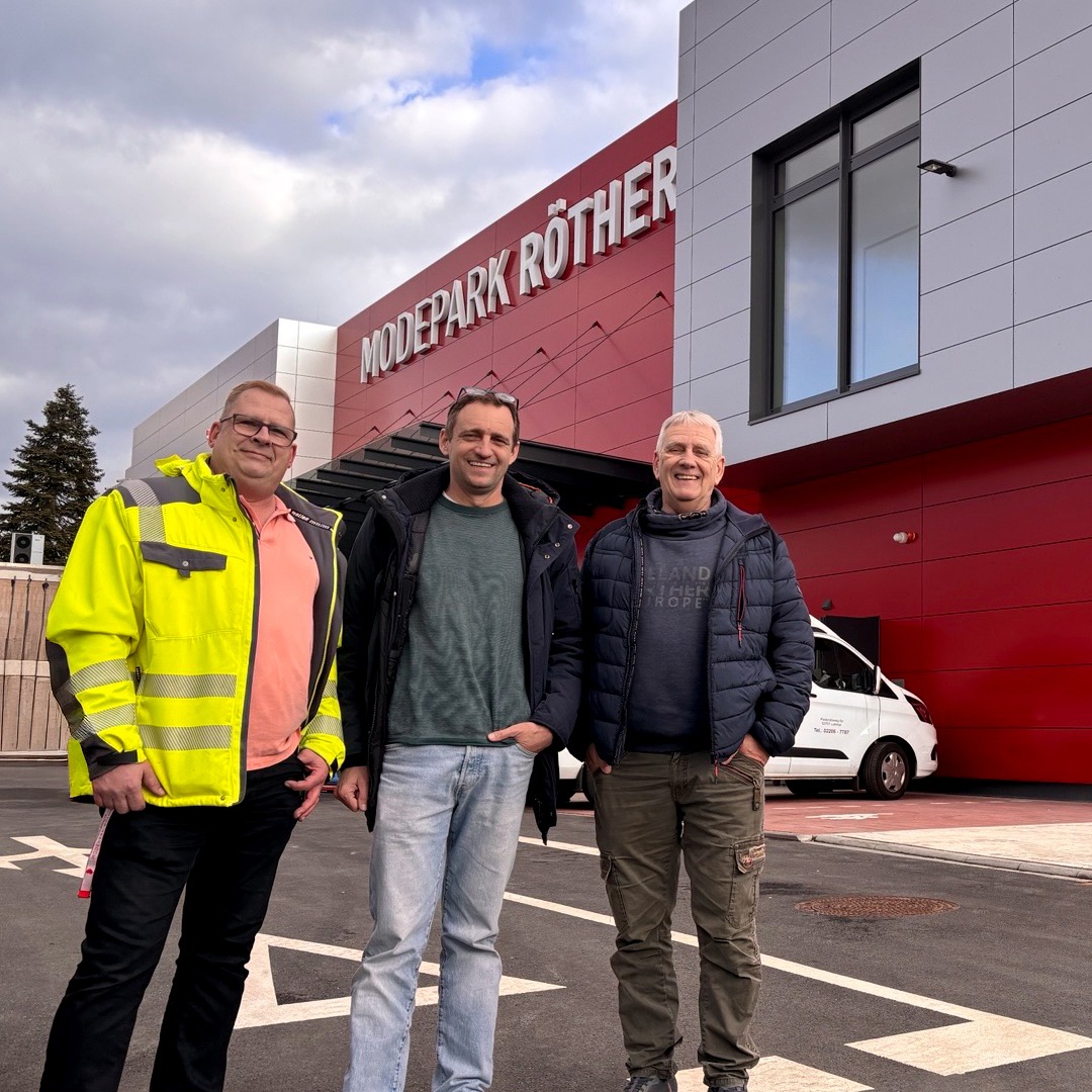 Drei Männer stehen vor einem Gebäude in Lohmar von Modepark Röther Drei Männer stehen vor einem Gebäude in Lohmar von Modepark Röther